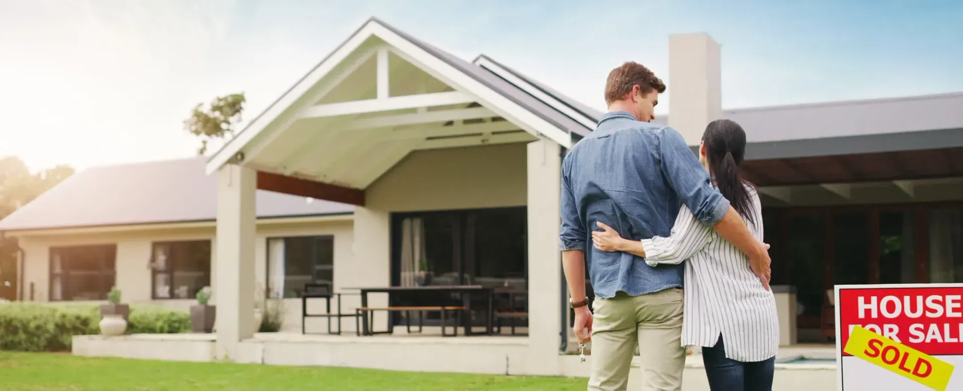 Couple standing together with house keys outside their new home